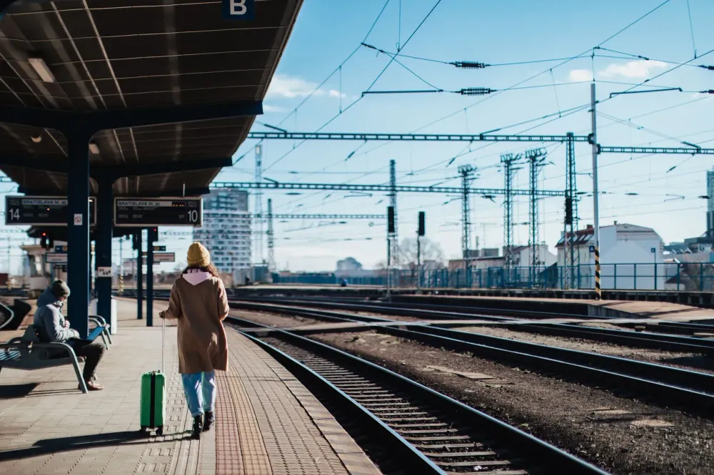 Single person waiting for train with luggage at an outdoor station